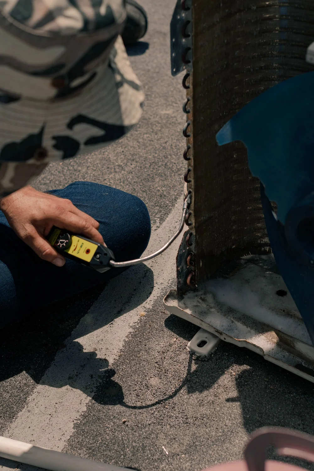 Stock photograph of a technician checking an outdoor air-conditioning unit with a meter; not Northline staff.