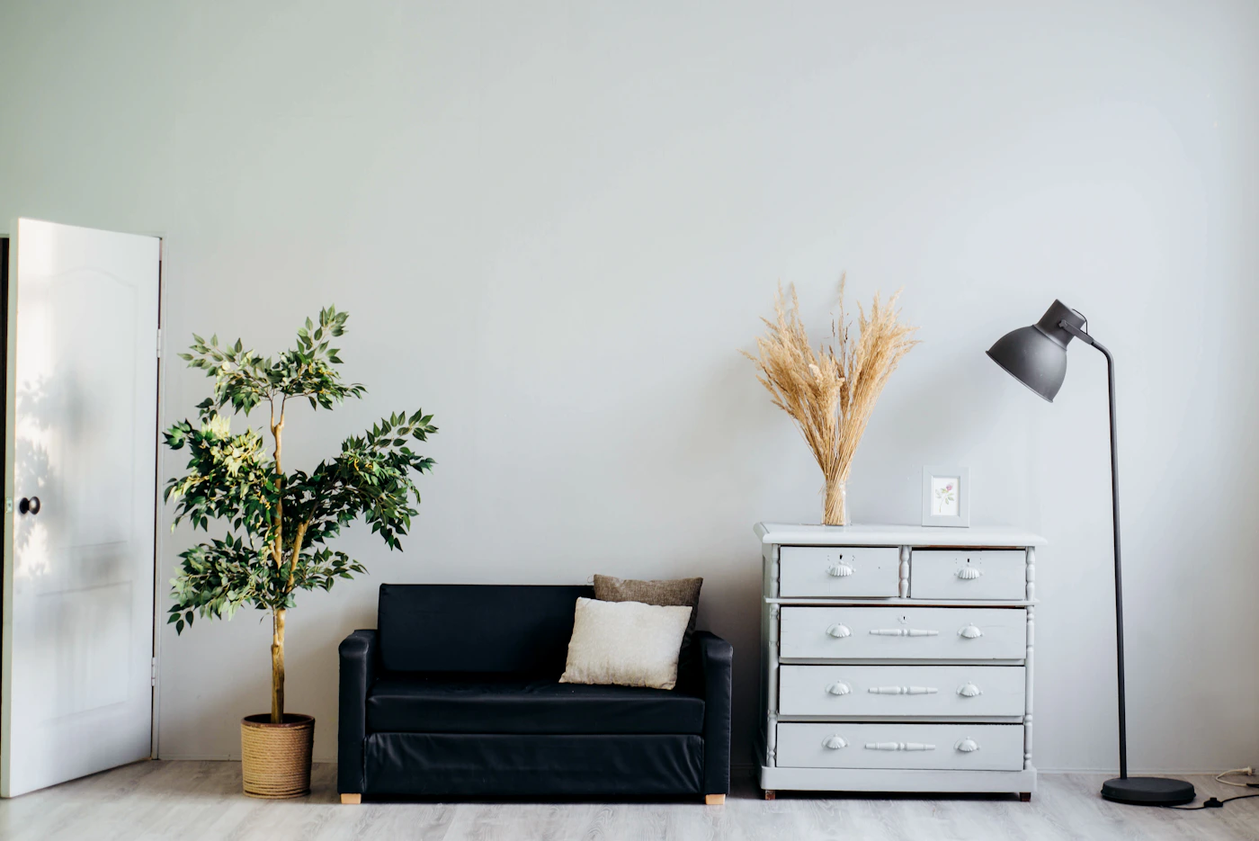 Light-gray walls, a black sofa and a white dresser.